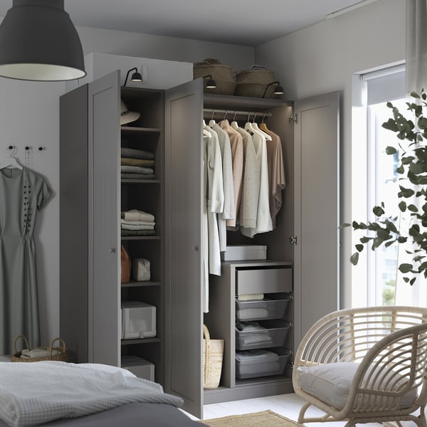 Grey PAX wardrobe with clothes and drawers, wicker chair, partial bed.