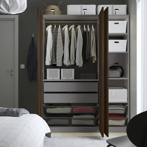 Open wardrobe displaying clothes, storage boxes, drawers, and mesh baskets inside, showcasing organised space and storage solutions.