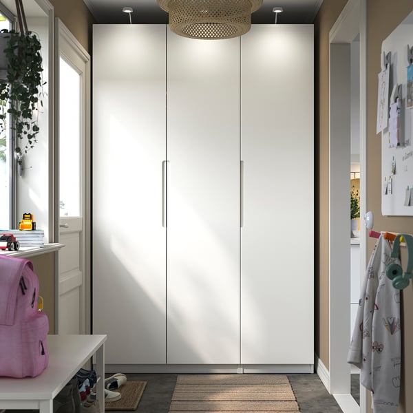 White PAX wardrobe centres room; tall, minimalist design, soft-close hinges.