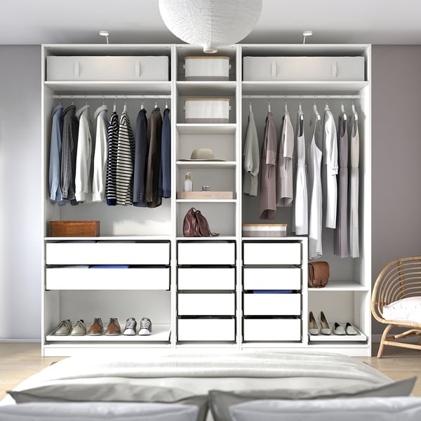 Modern bedroom with white PAX wardrobe. It hanging clothes, shelves with shoes, and storage boxes, all neatly organised.