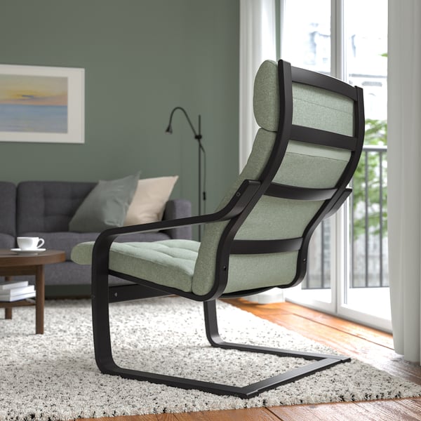 A modern living room shows a green cushioned, black-framed armchair with a high back for neck support.