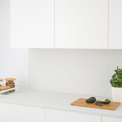 A kitchen counter with avocados on a cutting board and a potted plant.