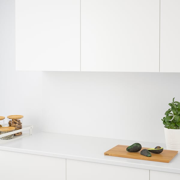 Modern kitchen counter with avocados and plant, featuring quartz-resistant wall and stylish storage.