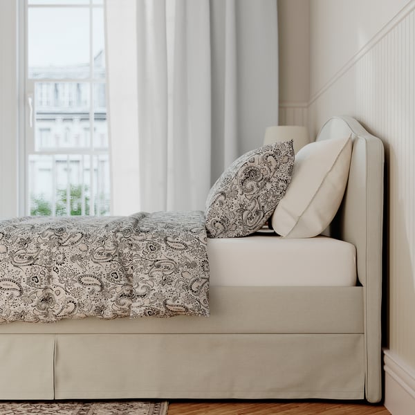 Bed frame with soft, padded headboard and removable cover, positioned near window.