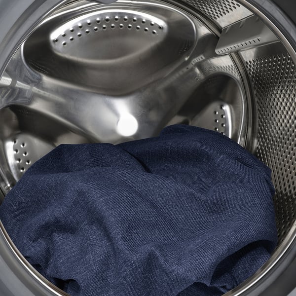 A washing machine with a dark blue garment placed inside. It highlights the functional interior drum of the appliance.