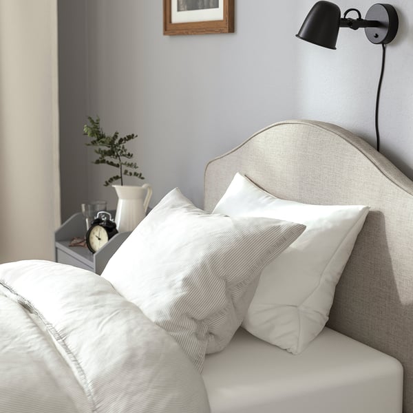 Modern bedroom with upholstered bed, crisp linens, and stylish bedside table.