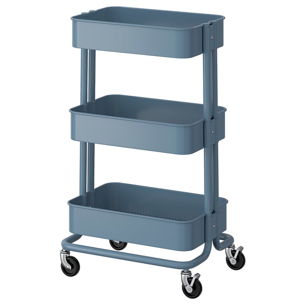A blue ikea RÅSKOG storage trolley with three tiers and wheels for mobility. Its sturdy with a metallic finish.