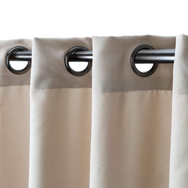 Two beige curtains hang from a metal rod via large black eyelets, offering privacy while filtering light.