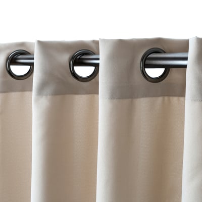 Two beige curtains hang from a metal rod via large black eyelets, offering privacy while filtering light.