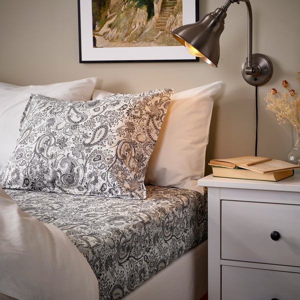 Cosy bed with paisley pillows, lamp, and books.