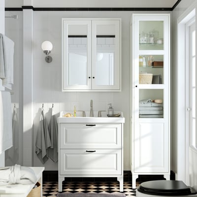 Modern white bathroom with integrated RUTSJÖN basin, tall cabinet, and hanging towels. Clean, minimalist design.