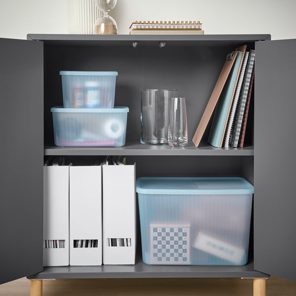 Shelf display of blue and white storage boxes, clear vases, and books. Boxes organise small items, are partly recycled, and semi-transparent.