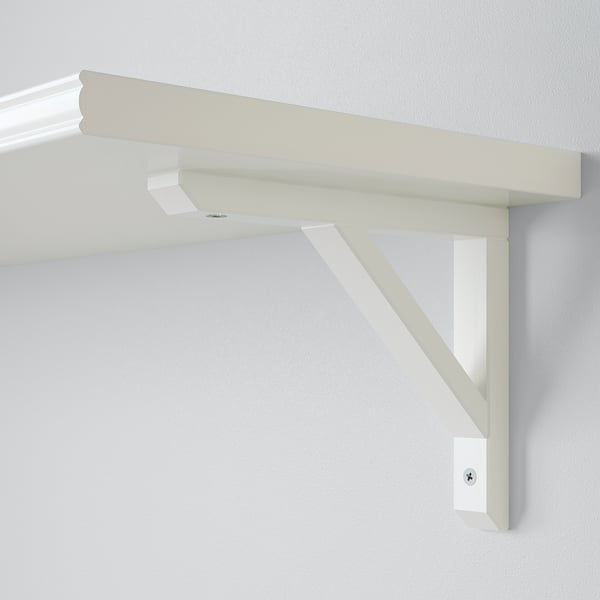 Minimalist shelf bracket in light wood, securely mounted on wall. Fits 20-30 cm deep shelves, reversible design.
