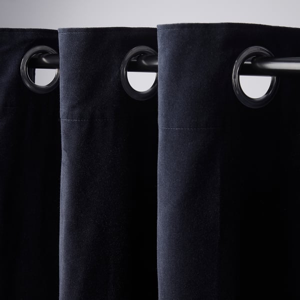 Black curtains with eyelet header hang elegantly, showing room-darkening fabric and smooth glide functionality.