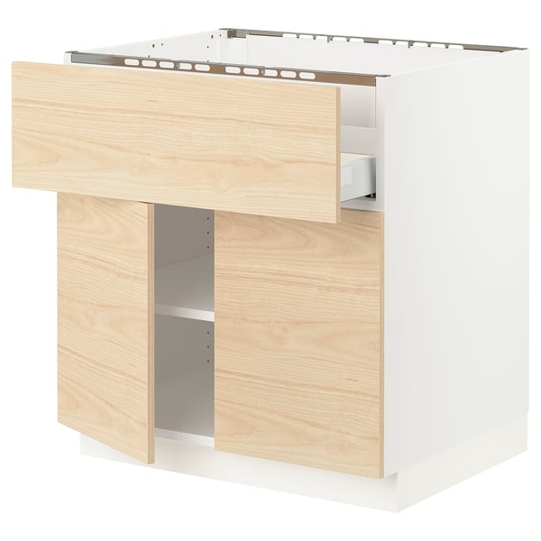 Wooden kitchen cabinet with open drawer, light ash finish.