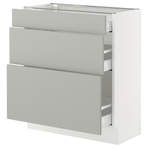 Modern light grey kitchen cabinets with three drawers and shelves.