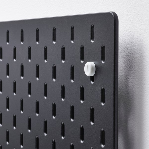 Black SKÅDIS pegboard with evenly spaced holes and wall anchor.