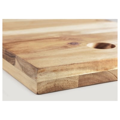 Rectangular wooden cutting board with smooth finish, slight grain texture, and small circular indentation near the edge, lying flat on a surface.
