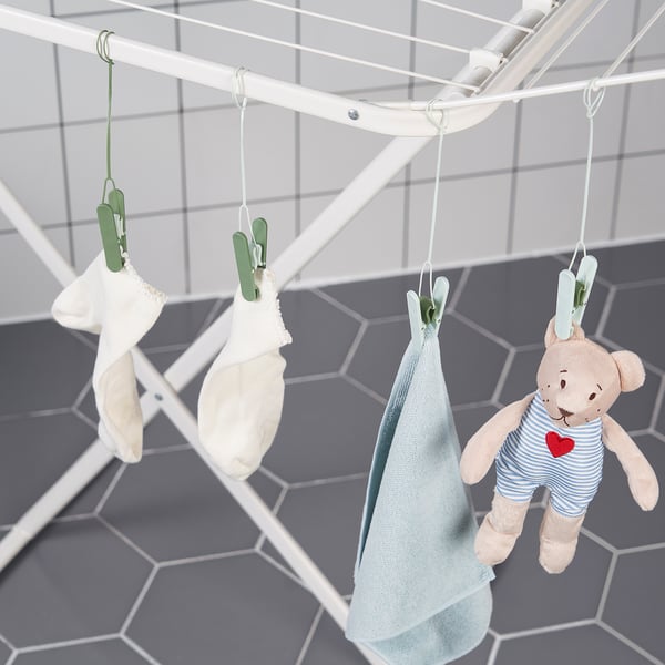 Clothespins hang clothes on drying rack, including baby items and a teddy bear.