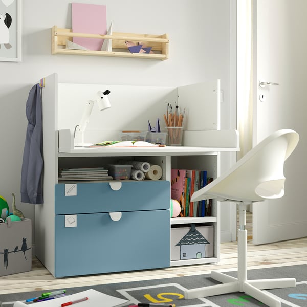 A white and blue childrens furniture set, featuring a desk with storage for school supplies, a chair, and a wall shelf with notebooks and decor items.