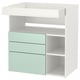 White & mint changing table with shelves and drawers for baby storage.