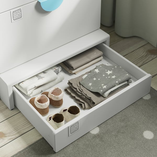 Open storage drawer of babys SMÅSTAD changing table. Shows folded linens, a blanket, and small cloth containers with items.
