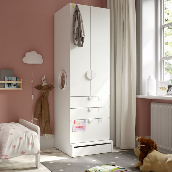 White SMÅSTAD wardrobe in childs room with drawers, cabinets, mirror, pink walls, heart bed, grey rug, plants, window.