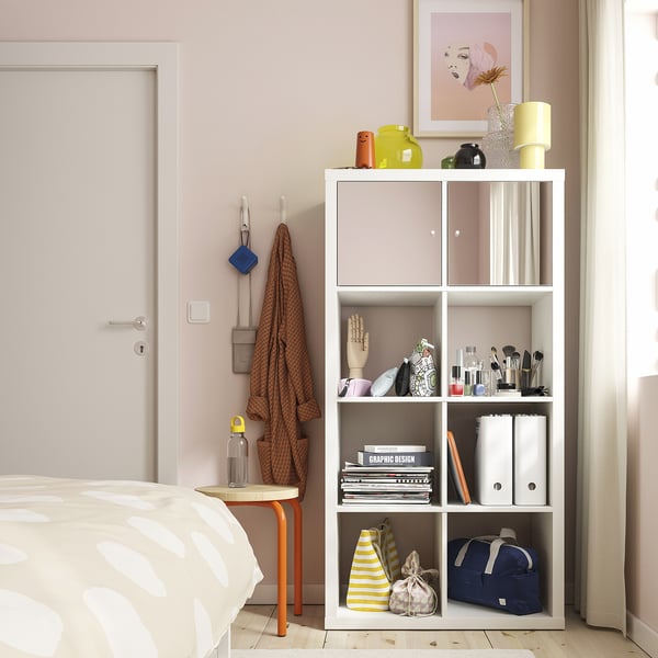Modern bedroom with pink walls, SNÖRAKA hook with a scarf, bookshelf, and a bed with pattern duvet.