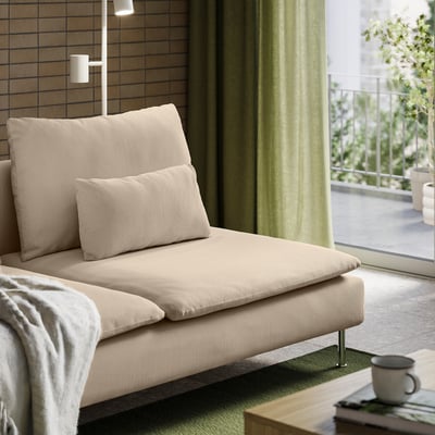 Modern beige sofa with pillows near window, offering comfort and support.