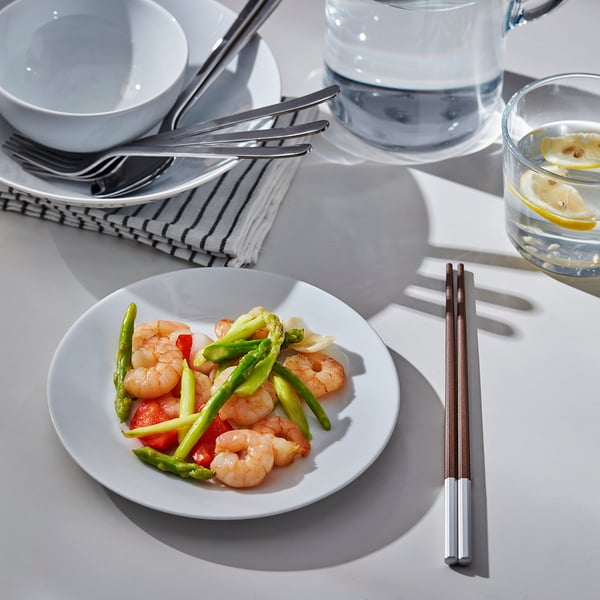 Plate of shrimp and vegetables with chopsticks and glasses.