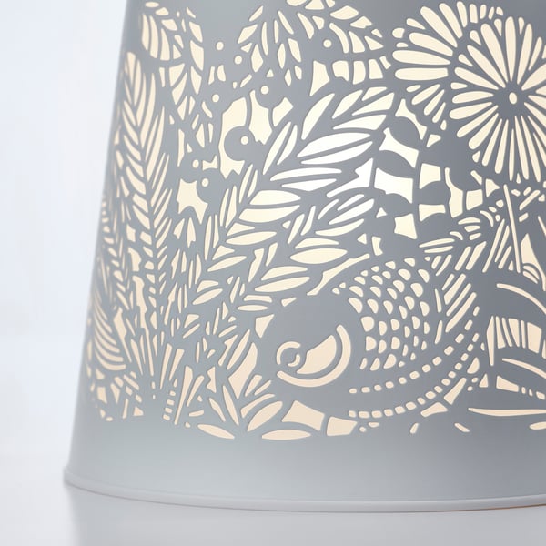 Intricate lamp with detailed nature-inspired cutouts, emitting soft, ambient light.