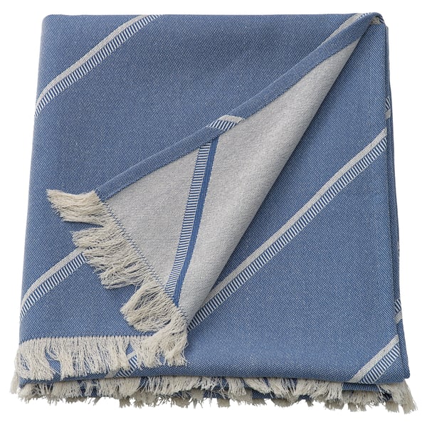 A folded blue SOLUPPGÅNG throw blanket with fringe and striped edges, featuring a blend of cotton and lyocell, designed for cosy use.