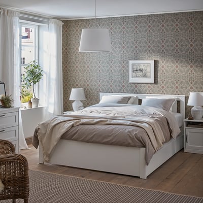 Modern bedroom with SONGESAND white bed, patterned wallpaper, light bedding, night lamps, and a large window with curtains.