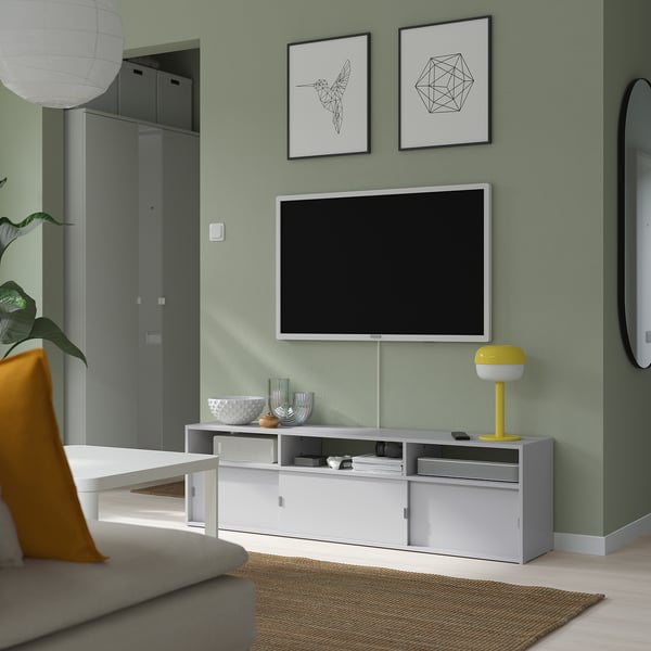 Modern living room with SPIKSMED tv bench in white, open/closed storage, yellow lamp, vases, art prints, beige rug.