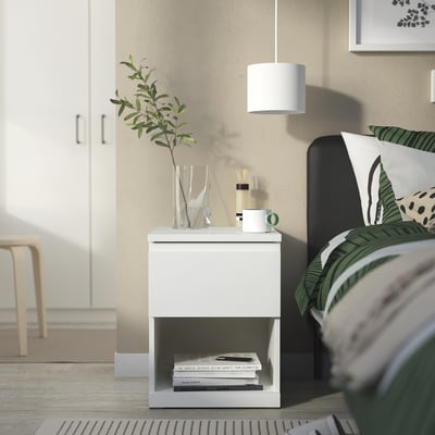 Bedside table, STORKLINTA, white, modern, square shape, smooth drawer, decorative items, green plant, lamp, books.