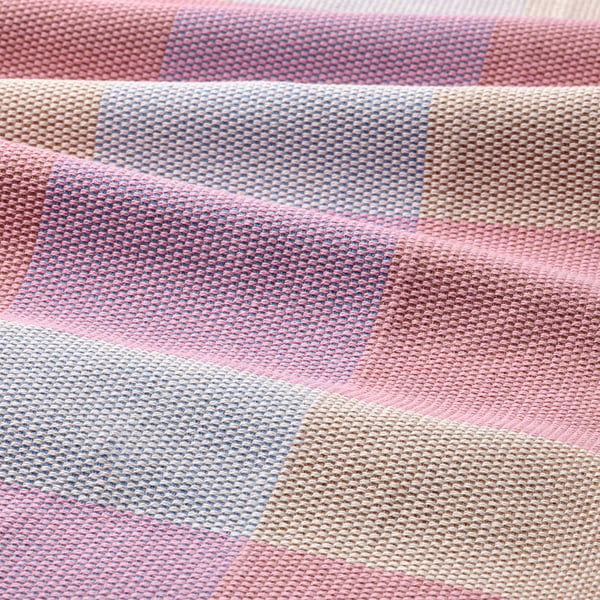 Vibrant, woven table runner in pink, blue, and cream stripes. Soft cotton texture, neatly folded.
