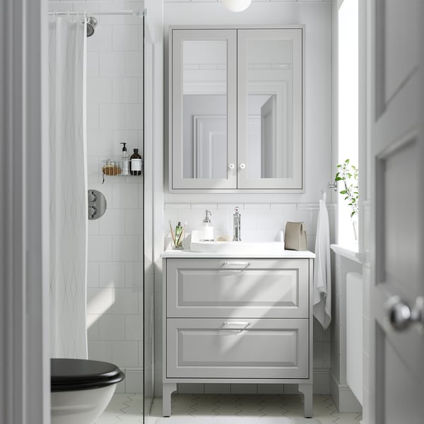 Grey TÄNNFORSEN vanity with large mirror. Vanity holds sink and items, mirror has bevelled details.