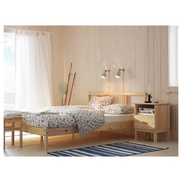 Bedroom with TARVA light wood bed and drawer; floral bedding; wall lamps; striped rug, simple scandinavian design.