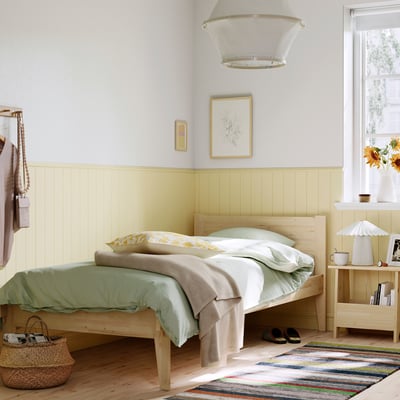 Scandinavian-style pine TAXÅSKLINT bed in cosy bedroom.