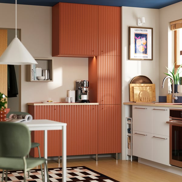 Modern kitchen featuring terrsjø red-brown cabinet sides, sleek surfaces, built-in coffee maker, and vibrant decor.