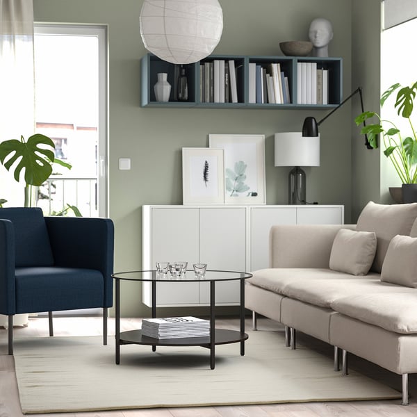 Modern living room with TIDTABELL table, rug, blue chair, sofa, vases, bookshelf, lamps, and large windows.