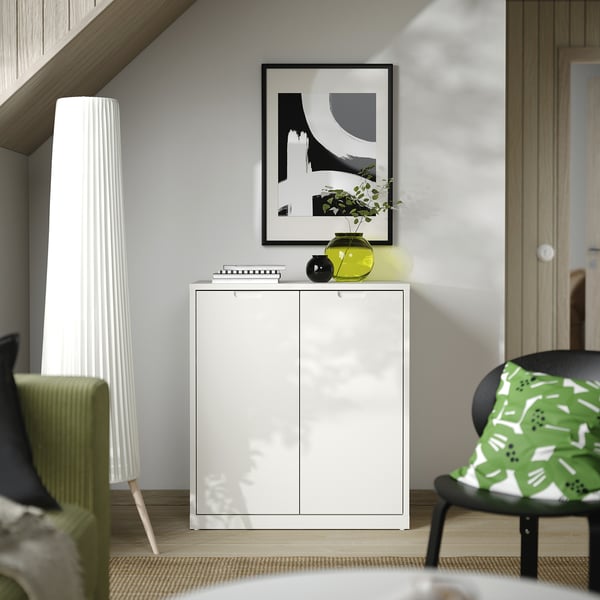 Modern living room with TONSTAD cabinet, abstract art, green plant in yellow vase, green patterned chair.