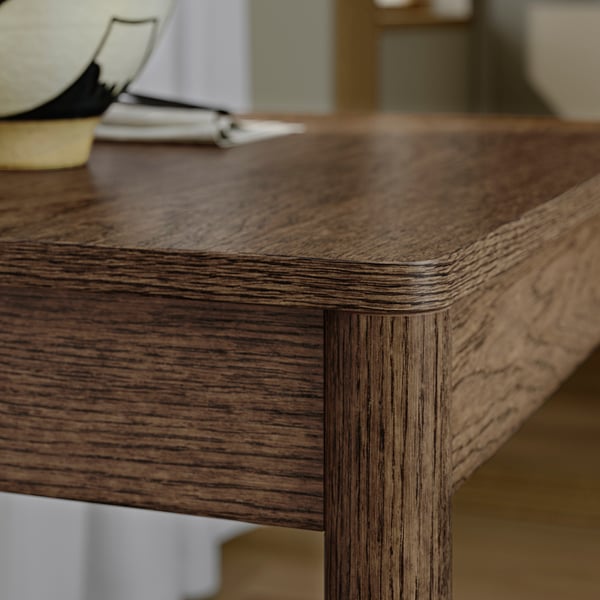 Close-up of TONSTAD tables rich oak veneer, showcasing smooth, rounded edges and natural grain patterns.
