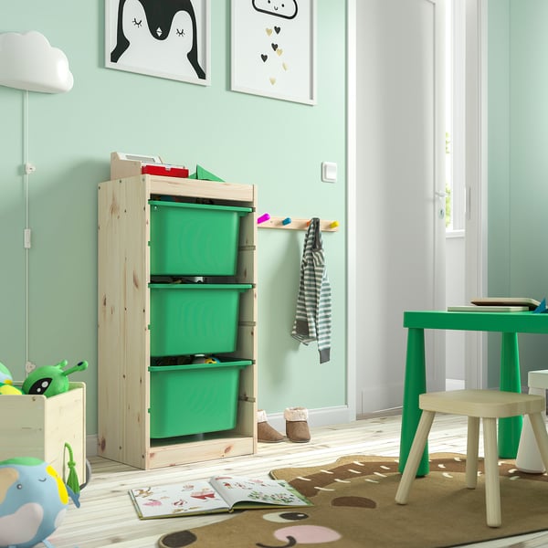 Playful kids room with light green TROFAST storage unit featuring three green plastic bins. Wall art and cosy furniture enhance the space.