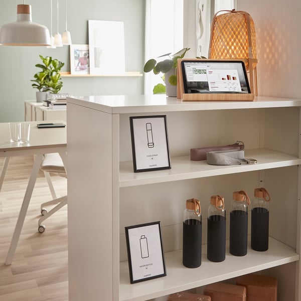 Room with trottén divider holding art, bottles, tablet, plant.