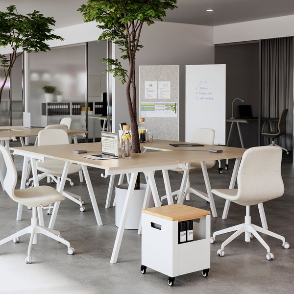 Modern office setup with a beige TROTTEN desk, white chairs, and a tree. Clean and organised with built-in table hooks.