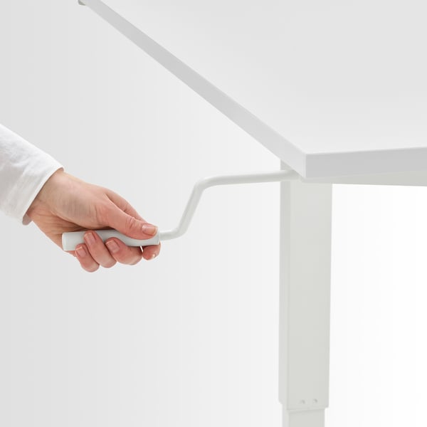Hand adjusting crank handle of TROTTEN height-adjustable desk, enabling smooth transition from sitting to standing.