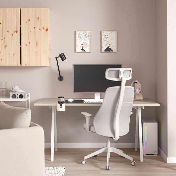 Minimalist home office: white TROTTEN chair, light wood desk, monitor, keyboard, mouse, headset, small speaker, wall art, lamp, cabinet.