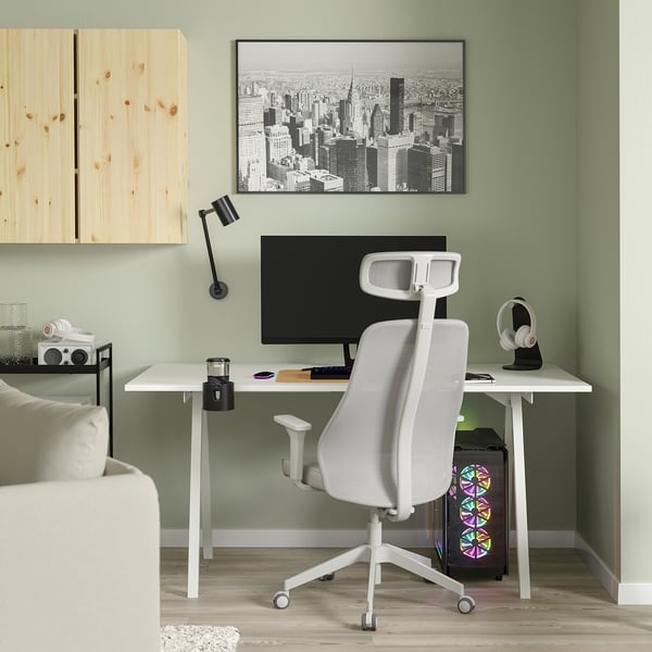 Home office with white desk, ergonomic chair, green wall, city art, wood floor.