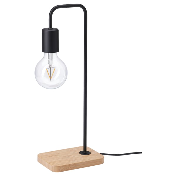 Simple black metal table lamp on bamboo base, clear light bulb.
